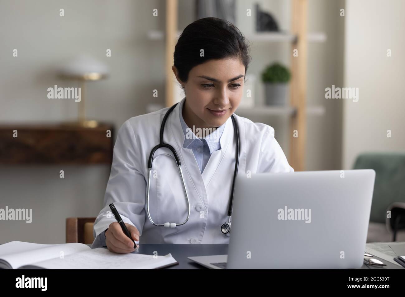 Concentrated millennial indian therapist working on computer. Stock Photo