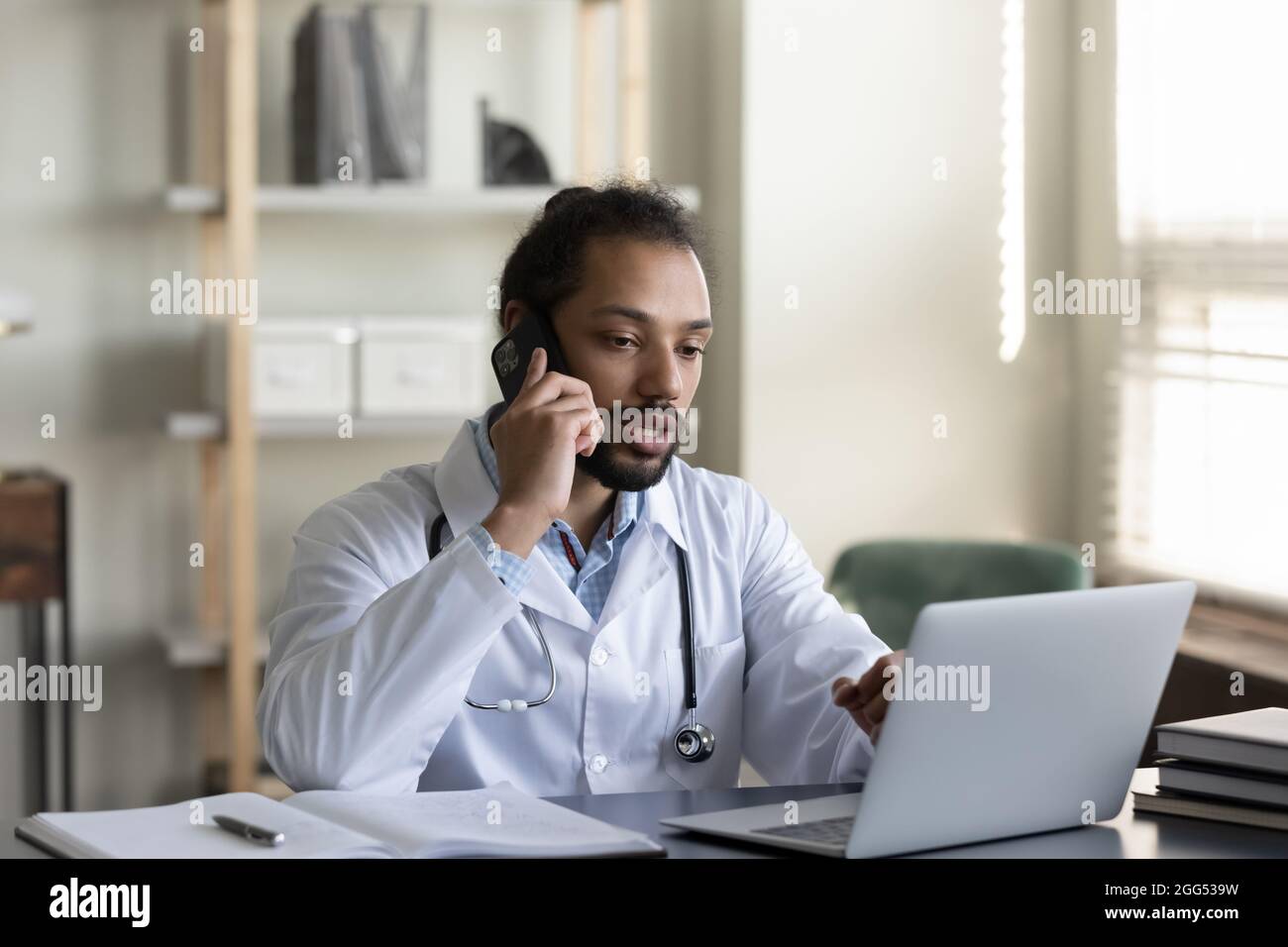 Concentrated young male african american doctor multitasking in office ...