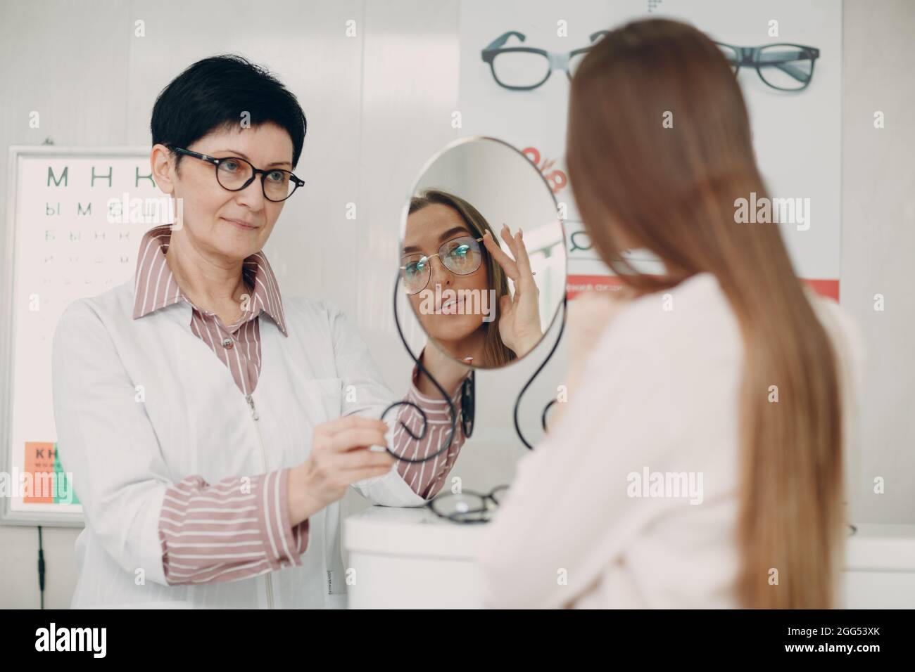 Young smiling woman smiling picking and choosing glasses at the optician corner at the shopping