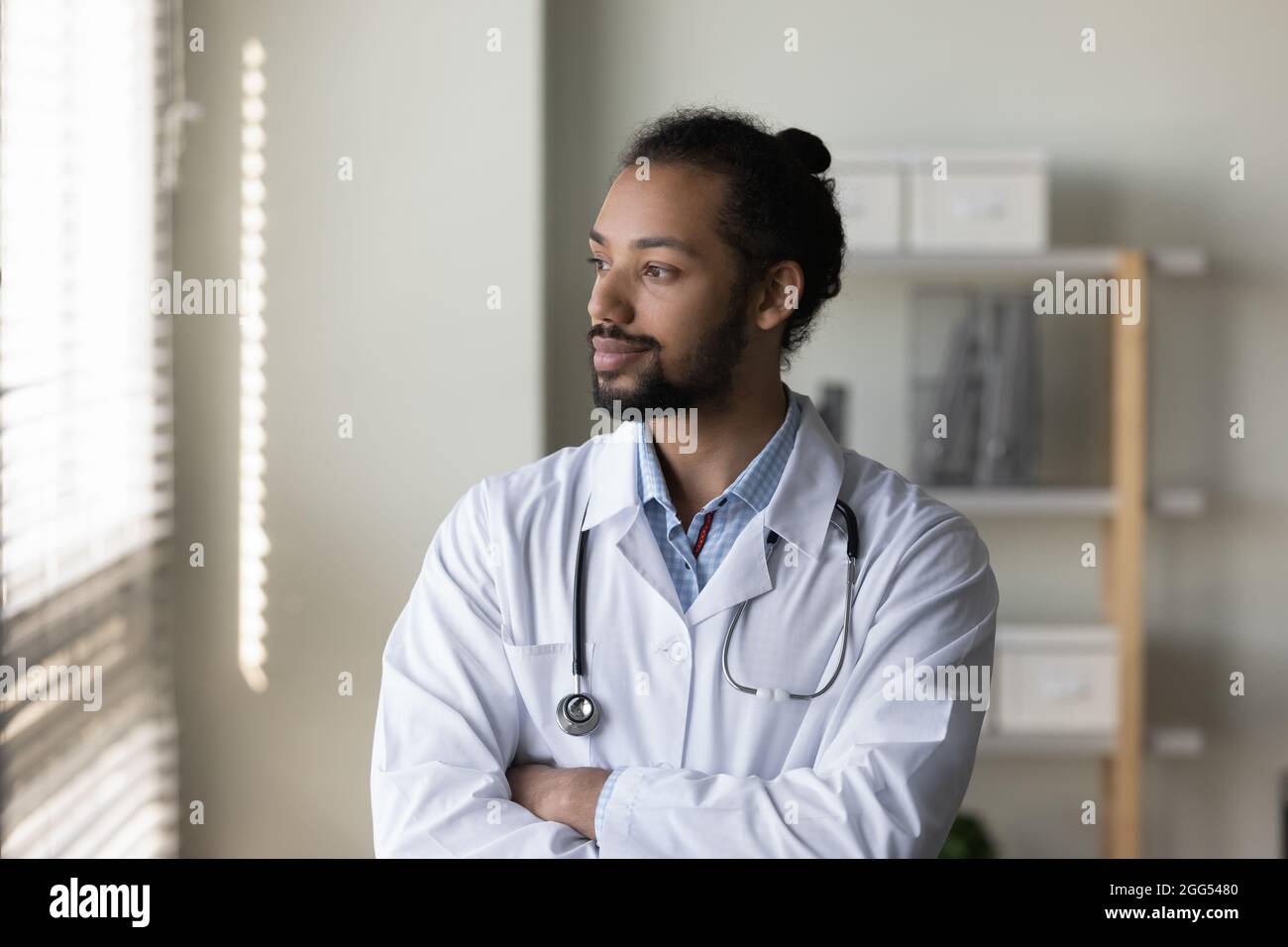 Thoughtful young male doctor looking in distance. Stock Photo