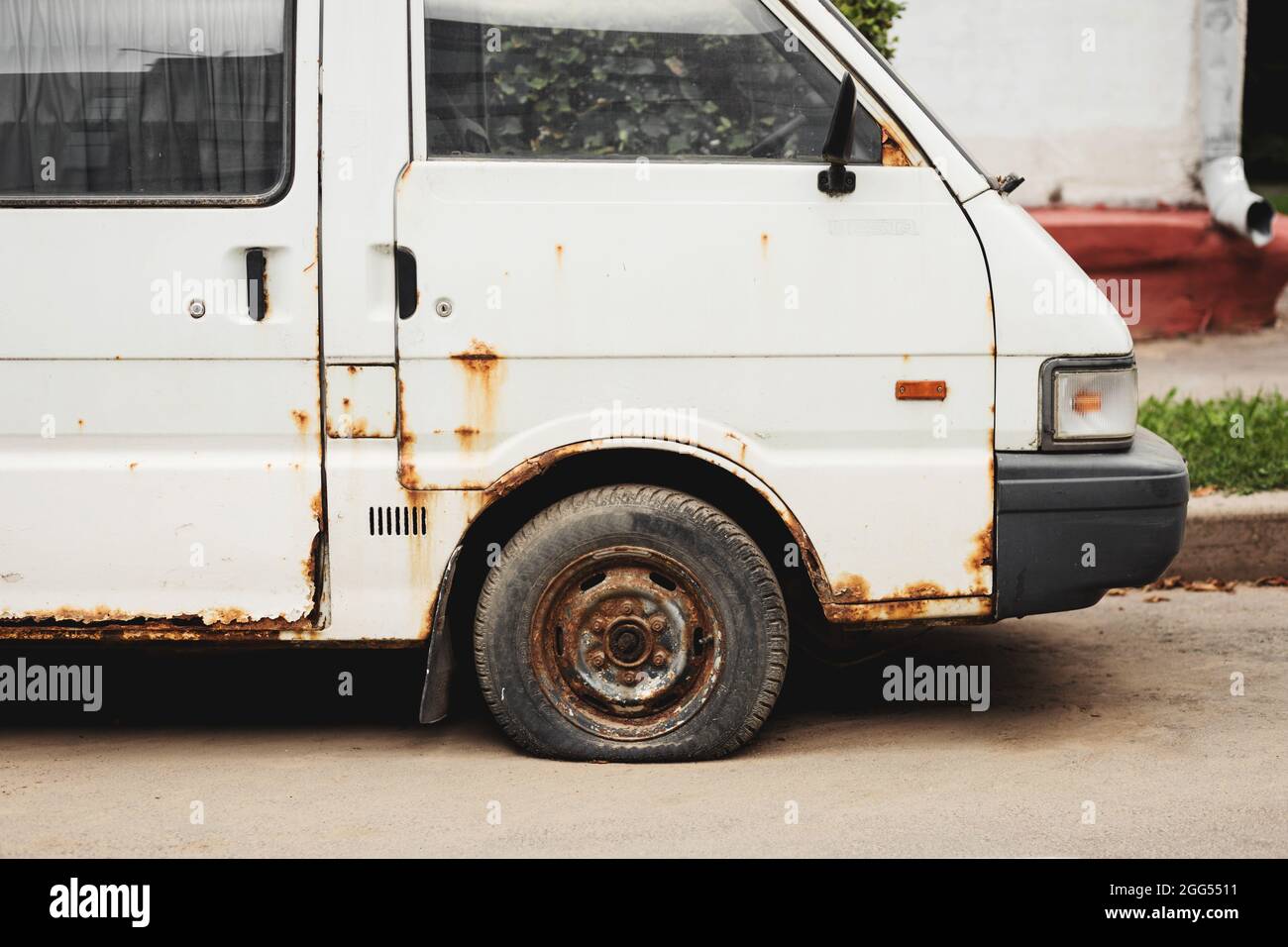 White rusty abandoned compact van. Unnecessary malfunctioning car junk truck abandoned on the side of the road Stock Photo