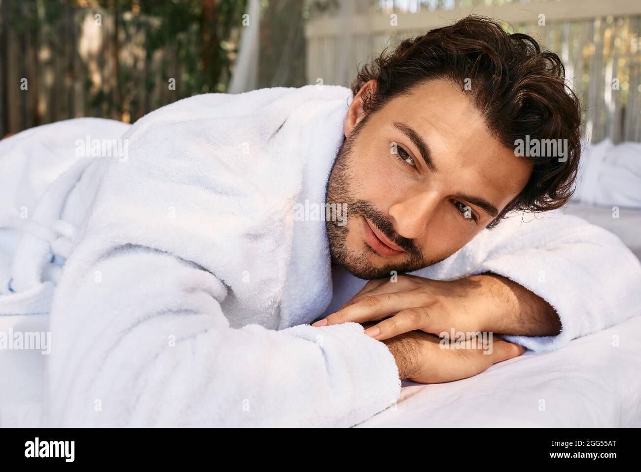 Spa. Portrait of handsome man wearing a bathrobe lying on a massage table at wellness centre Stock Photo