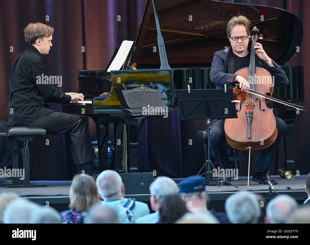 28 August 2021, Brandenburg, Neuhardenberg: Jan Vogler (r), musician on the cello, plays together with Antti Siirala on the grand piano on stage at the end of the course "Meisterschüler-Meister" for the summer program at Schloss Neuhardenberg. For the seventh time, the Stiftung Schloss Neuhardenberg and cellist Jan Vogler invited young musicians from Europe to a one-week chamber music workshop at Schloss Neuhardenberg. The programme of the open-air event series "Into the Open Air!" will run until 05.09.2021. Many different concerts, readings and talks will take place under the large tent roof Stock Photo