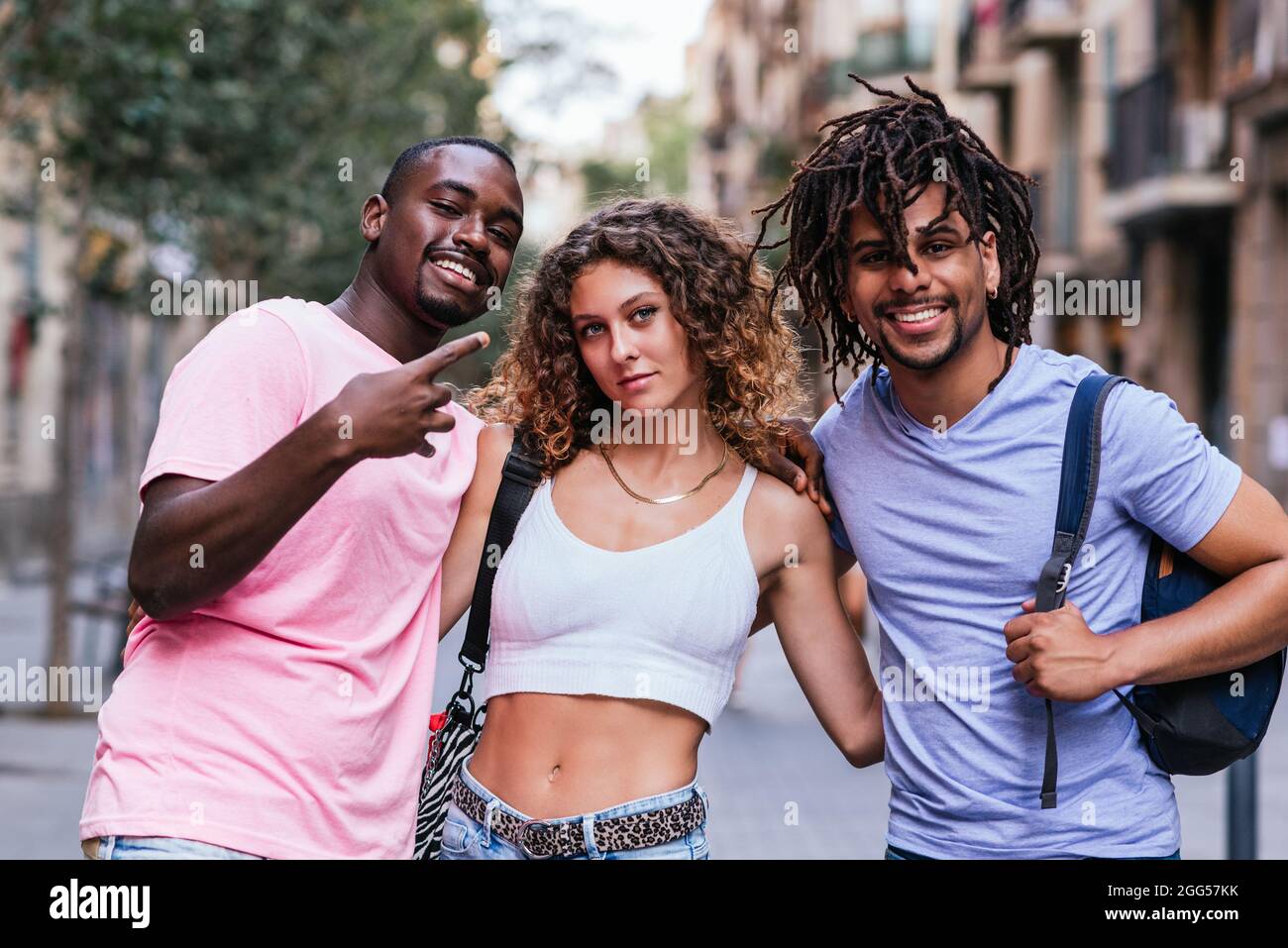 horizontal portrait of a group of friends in the streets of Barcelona. One caucasian woman, a latin american man and an afro american man Stock Photo