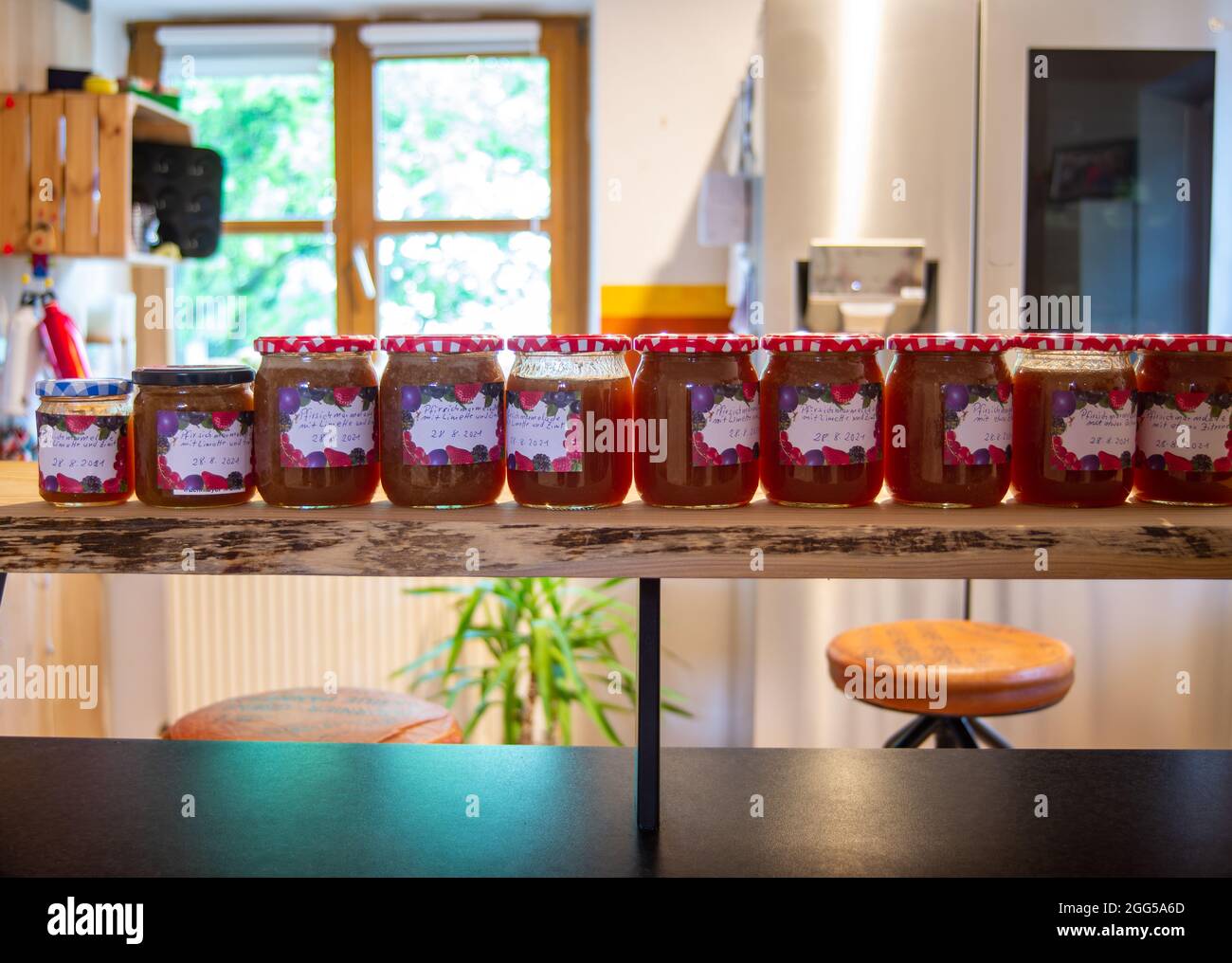 Freshly filled jars of marmelade standing in a kitchen. Stock Photo