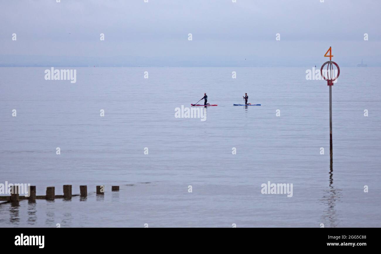 Portobello, Edinburgh, Scotland, UK weather. 29th August 2021. Dull and Cloudy at the seaside, temperature 15 degrees centigrade for those out exercising. Pictured: two paddleboarders paddling on the Firth of Forth. Credit: Arch White/Alamy Live News Stock Photo