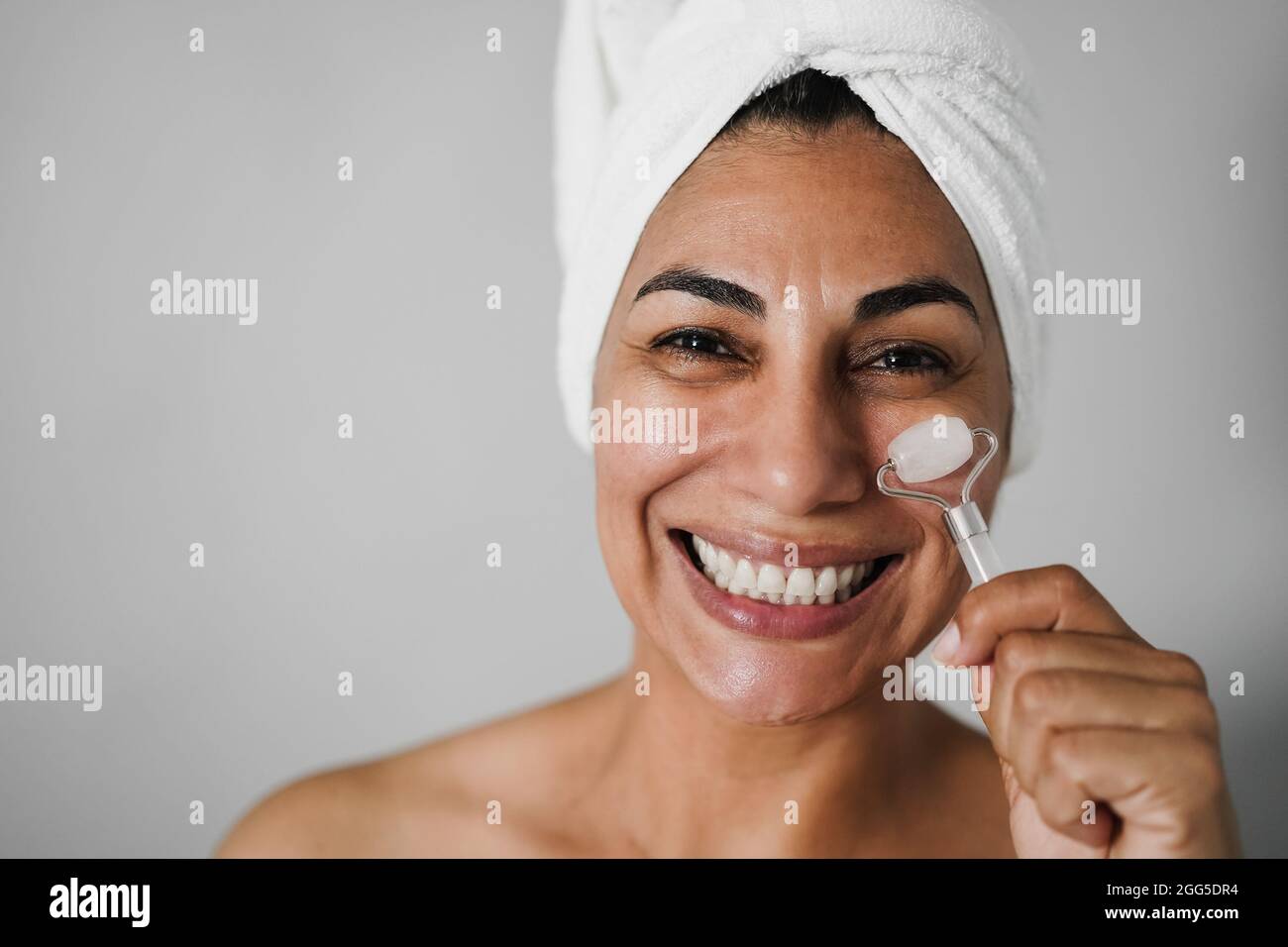 Senior woman doing skin care treatment using face roller Main focus