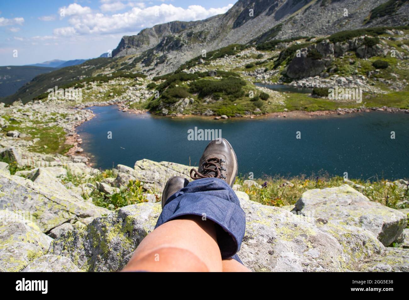 woman legs with trekking boots over glacier lake in mountains freedom and slow travel concept Stock Photo