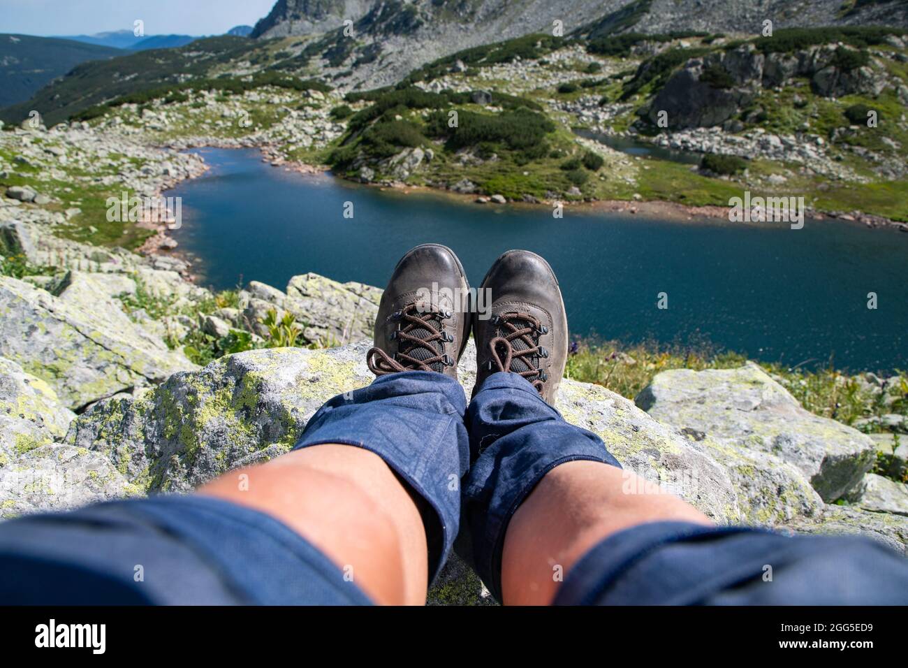 woman legs with trekking boots over glacier lake in mountains freedom and slow travel concept Stock Photo