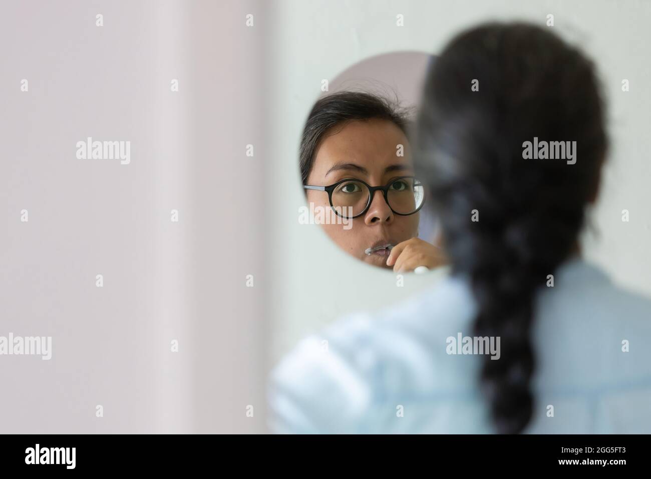 Beautiful Mexican female brushing her teeth in the morning in the