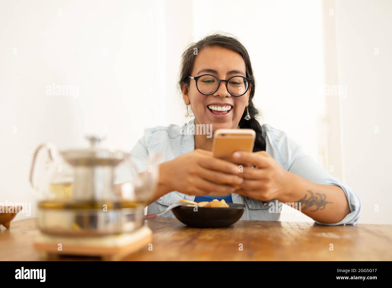 Beautiful Mexican female sitting in the kitchen texting and having ...