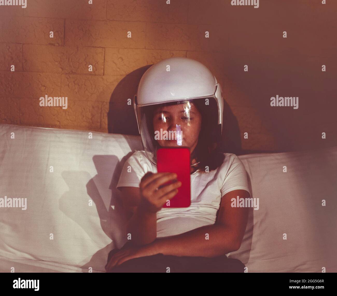 Little girl dreams of becoming an astronaut and flying into space holding mobile phone in the dark room Stock Photo