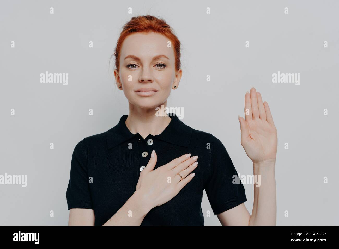 Beautiful red haired patriotic woman swearing with hand on chest and open palm Stock Photo