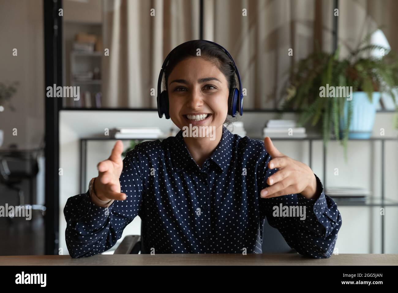 Head shot portrait of smiling Indian businesswoman in headphones speaking Stock Photo