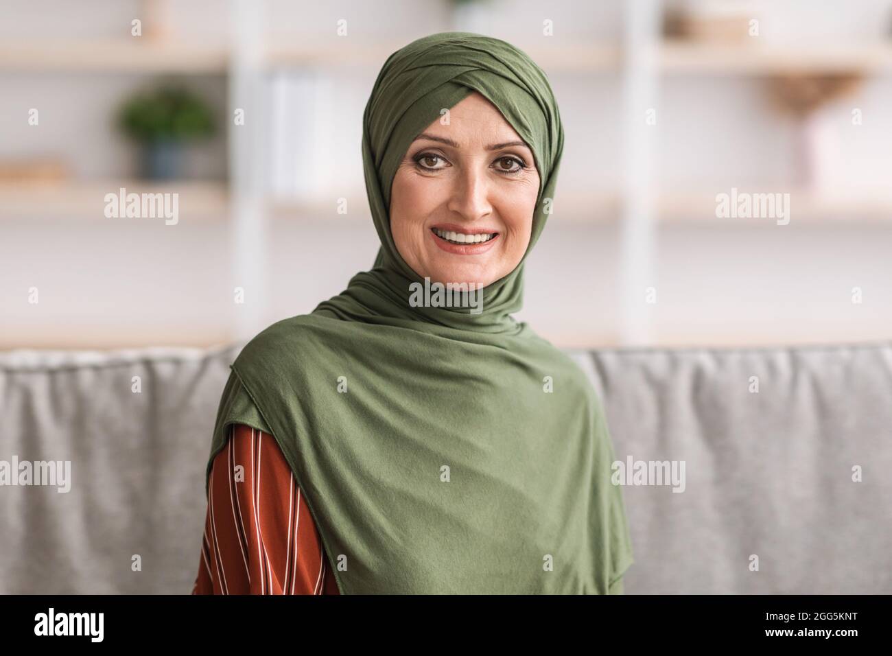 Portrait Of Happy Mature Middle-Eastern Woman Wearing Hijab At Home Stock Photo