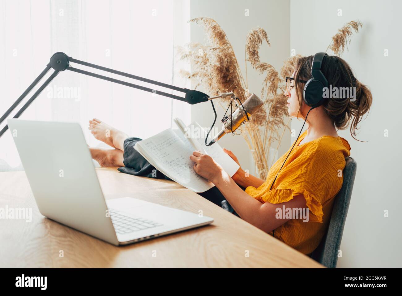 Woman sits with his feet up on his desk and recording live podcast. Female  podcaster streaming her voice into microphone at home studio Stock Photo -  Alamy