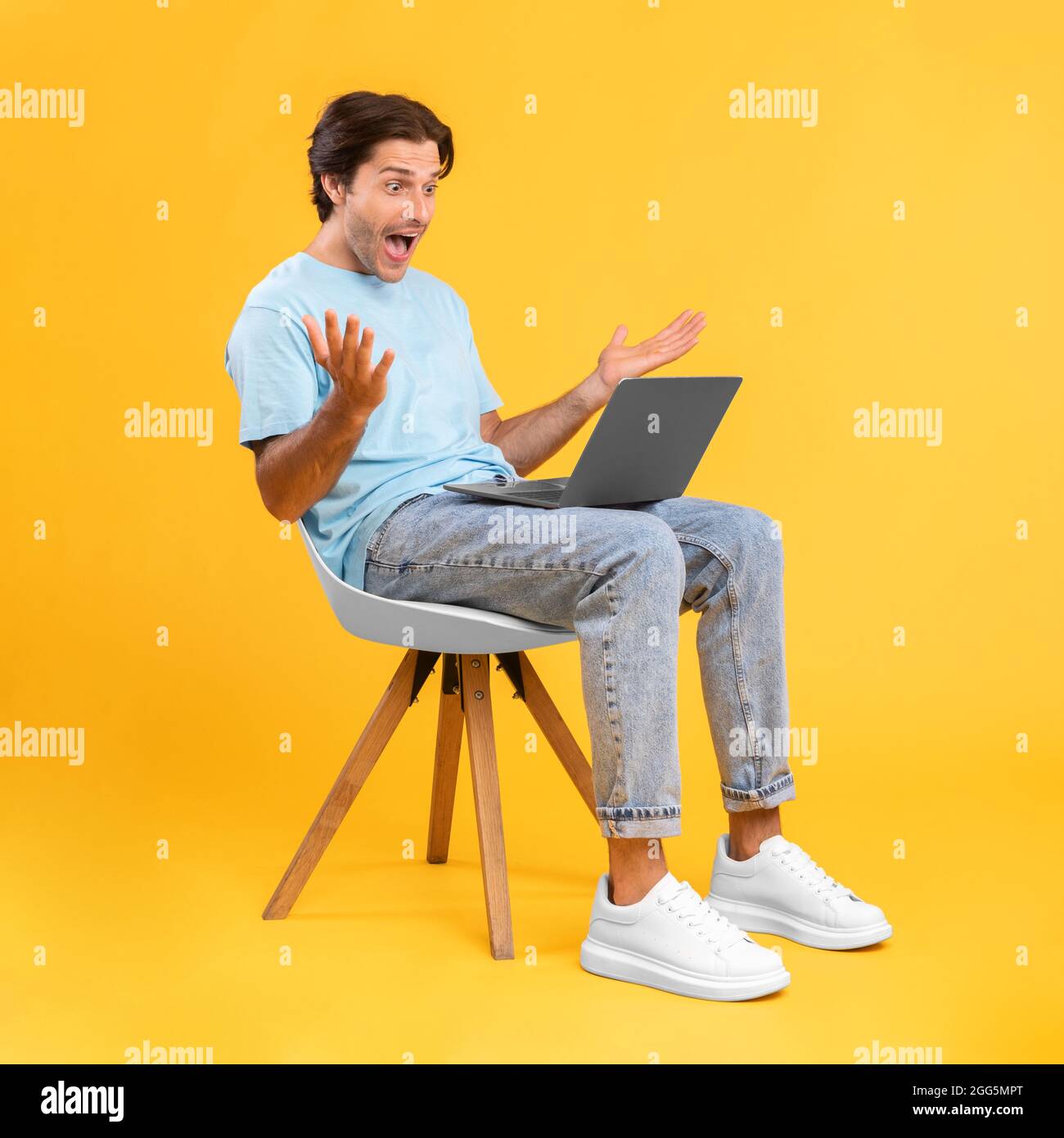 Excited guy using laptop celebrating success sitting on chair Stock Photo
