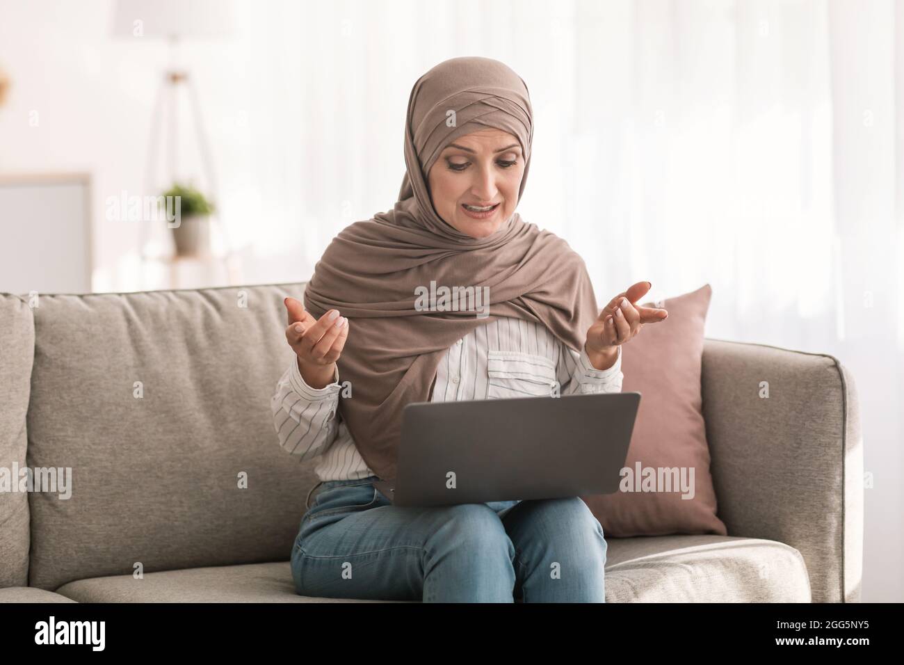 Middle-Eastern Woman Video Calling Using Laptop Sitting On Sofa Indoor Stock Photo