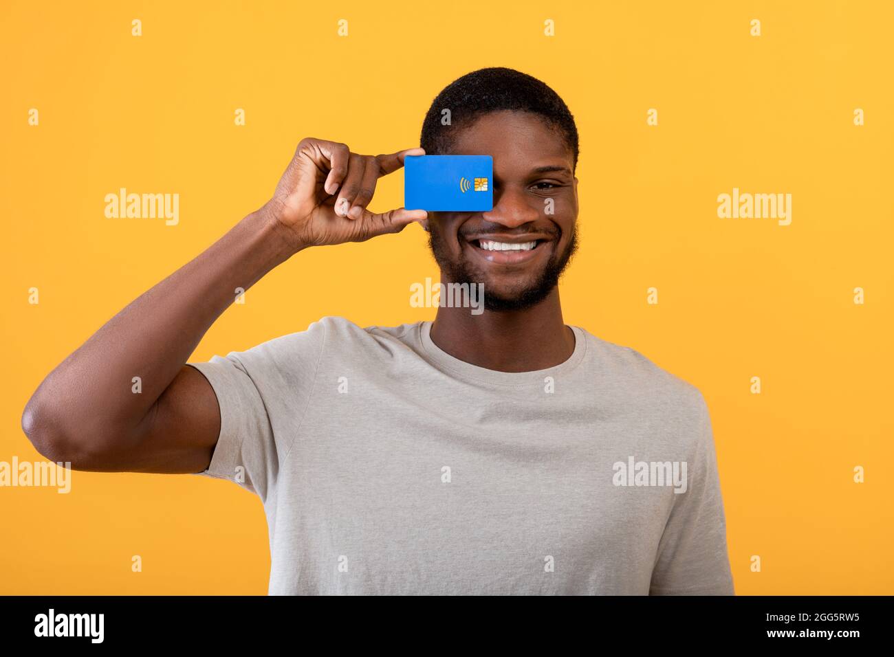Excited black guy holding credit card in front of his eye, promoting ...