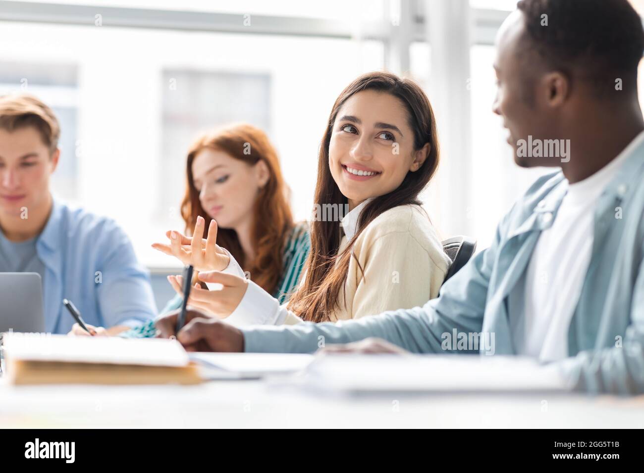 International group of people sitting at desk and talking Stock Photo