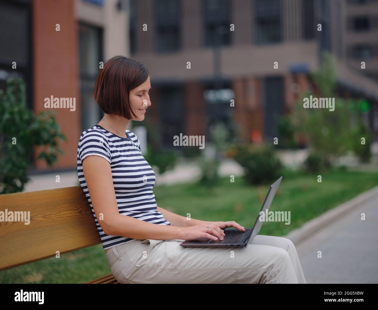 Young asian female student working at laptop sit down on bench outside ...