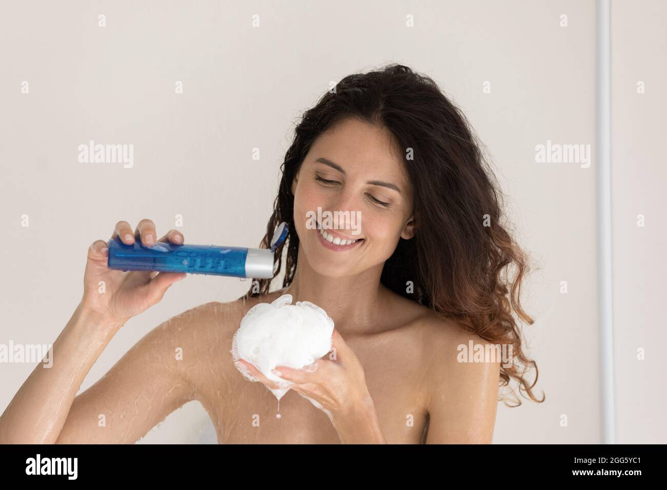 Happy young woman applying shower gel on puff Stock Photo Alamy
