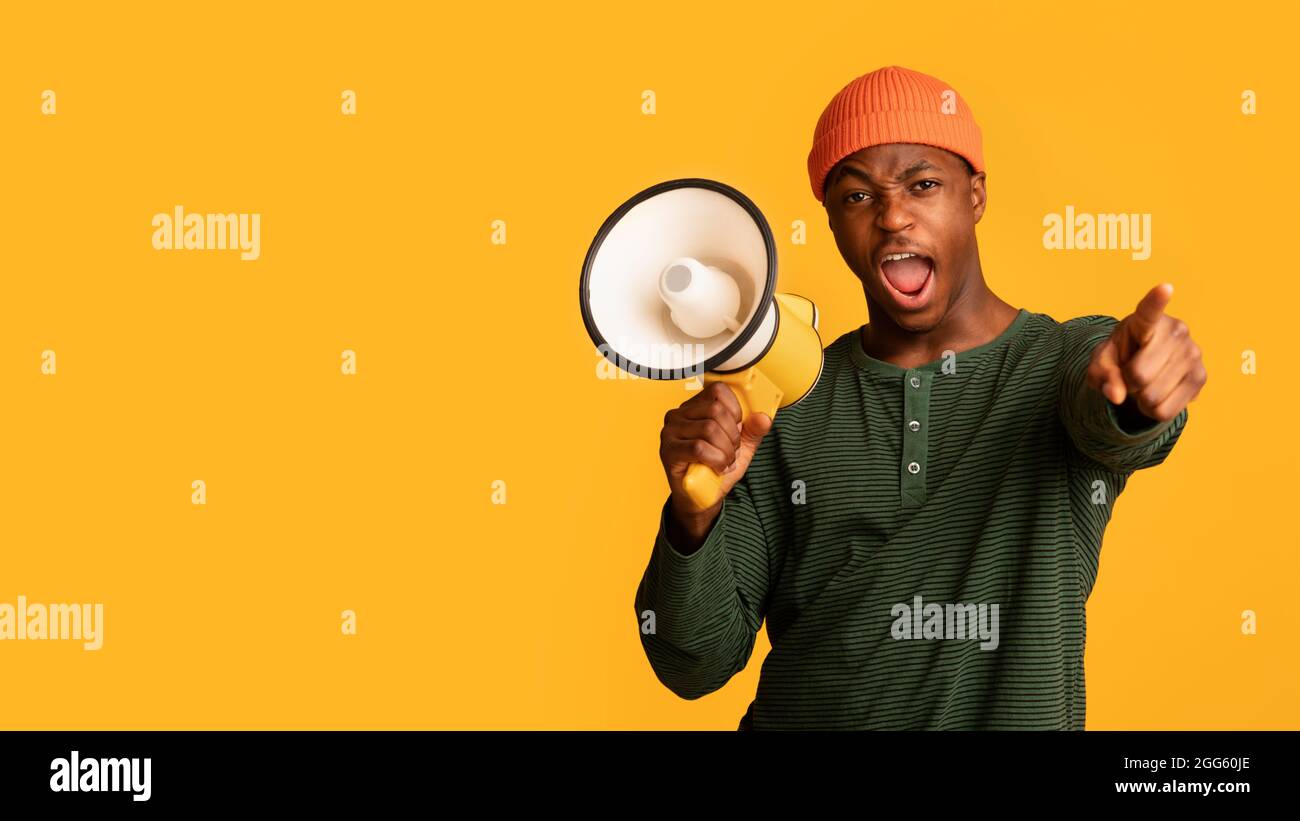 Attention. Emotional Black Guy With Megaphone Shouting And Pointing Finger At Camera Stock Photo