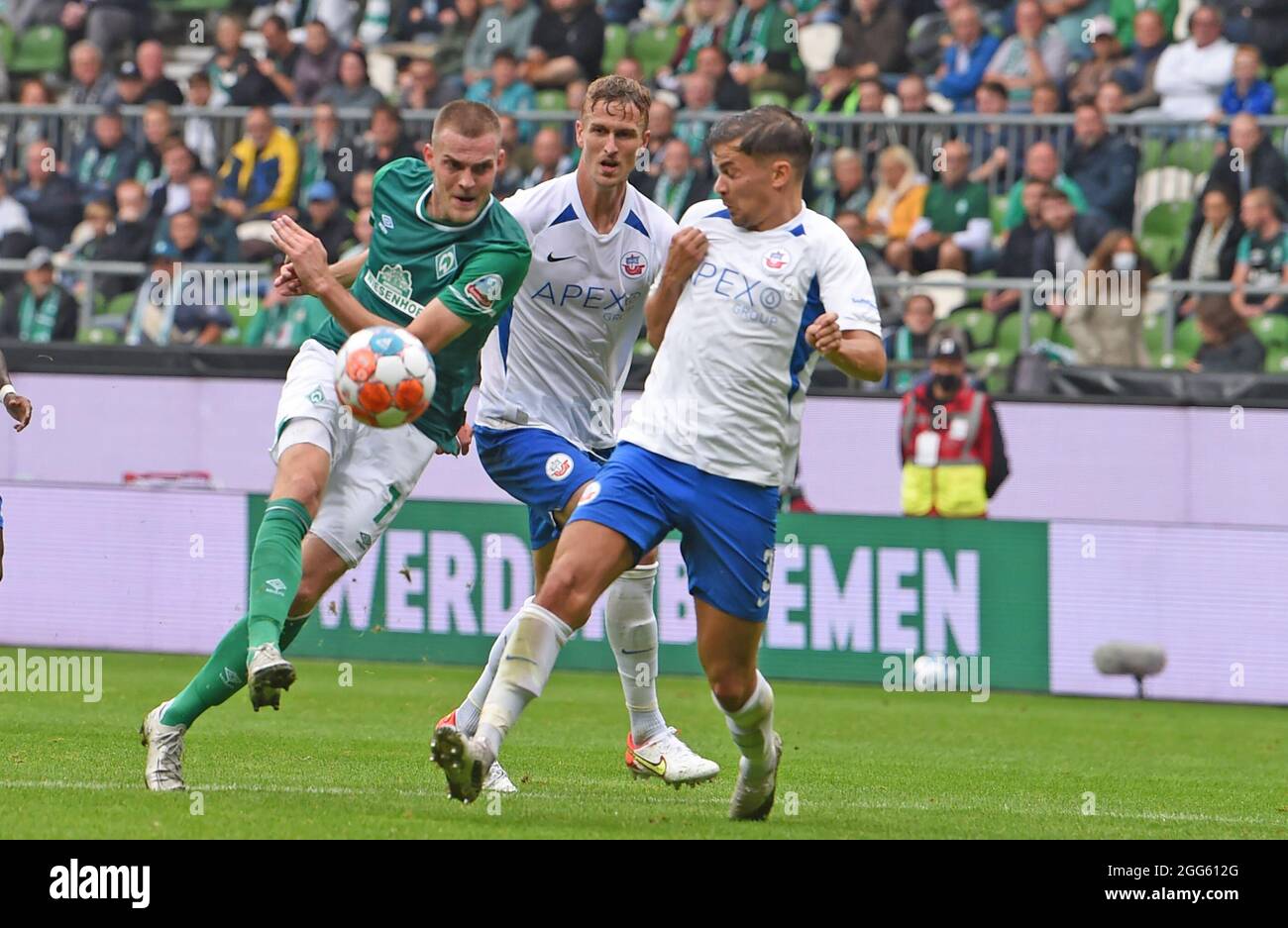 Bremen, Germany. 29th Aug, 2021. Football: 2. Bundesliga, Werder Bremen - Hansa Rostock, Matchday 5. Werder's Marvin Ducksch (l) gets a shot off against Rostock's Julian Riedel and Thomas Meißner. Credit: Carmen Jaspersen/dpa - IMPORTANT NOTE: In accordance with the regulations of the DFL Deutsche Fußball Liga and/or the DFB Deutscher Fußball-Bund, it is prohibited to use or have used photographs taken in the stadium and/or of the match in the form of sequence pictures and/or video-like photo series./dpa/Alamy Live News Stock Photo