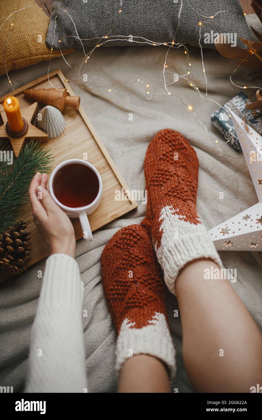 Woman legs in warm socks on soft blanket with cup of tea, christmas stars,  golden lights, trees, candle and pillows, top view. Cozy relaxing moments a  Stock Photo - Alamy