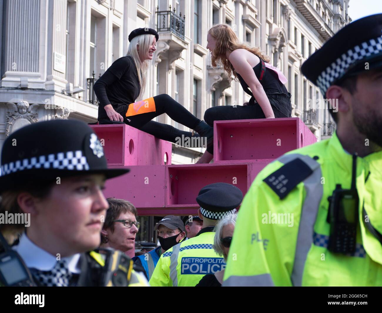 Extinction Rebellion protest wednesday 25th August 2021, London UK. Protesters sit on top of giant pink table in Oxford Circus London Stock Photo