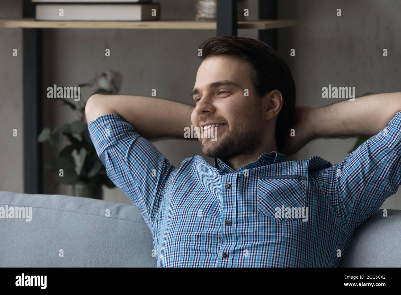 Happy thoughtful millennial guy relaxing on sofa at home Stock Photo