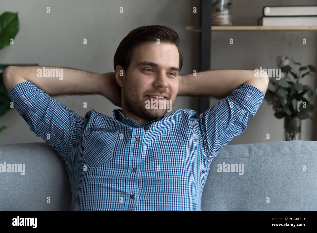 Thoughtful smiling guy relaxing on couch, looking away and smiling Stock Photo