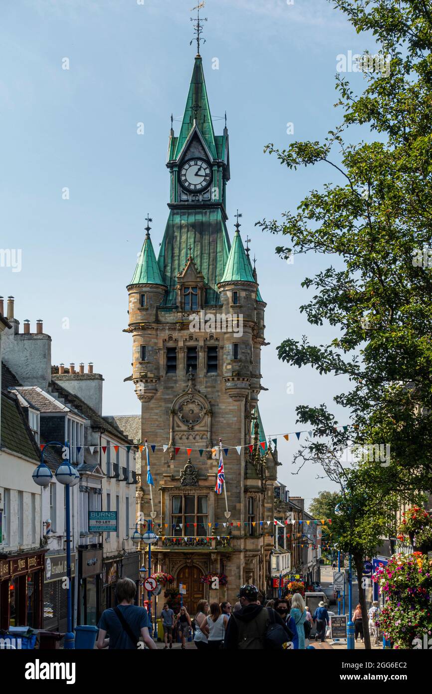 The  clock tower of Dunfermline City Chambers soars above shoppers in the High Street below. Fife, Scotland. Stock Photo