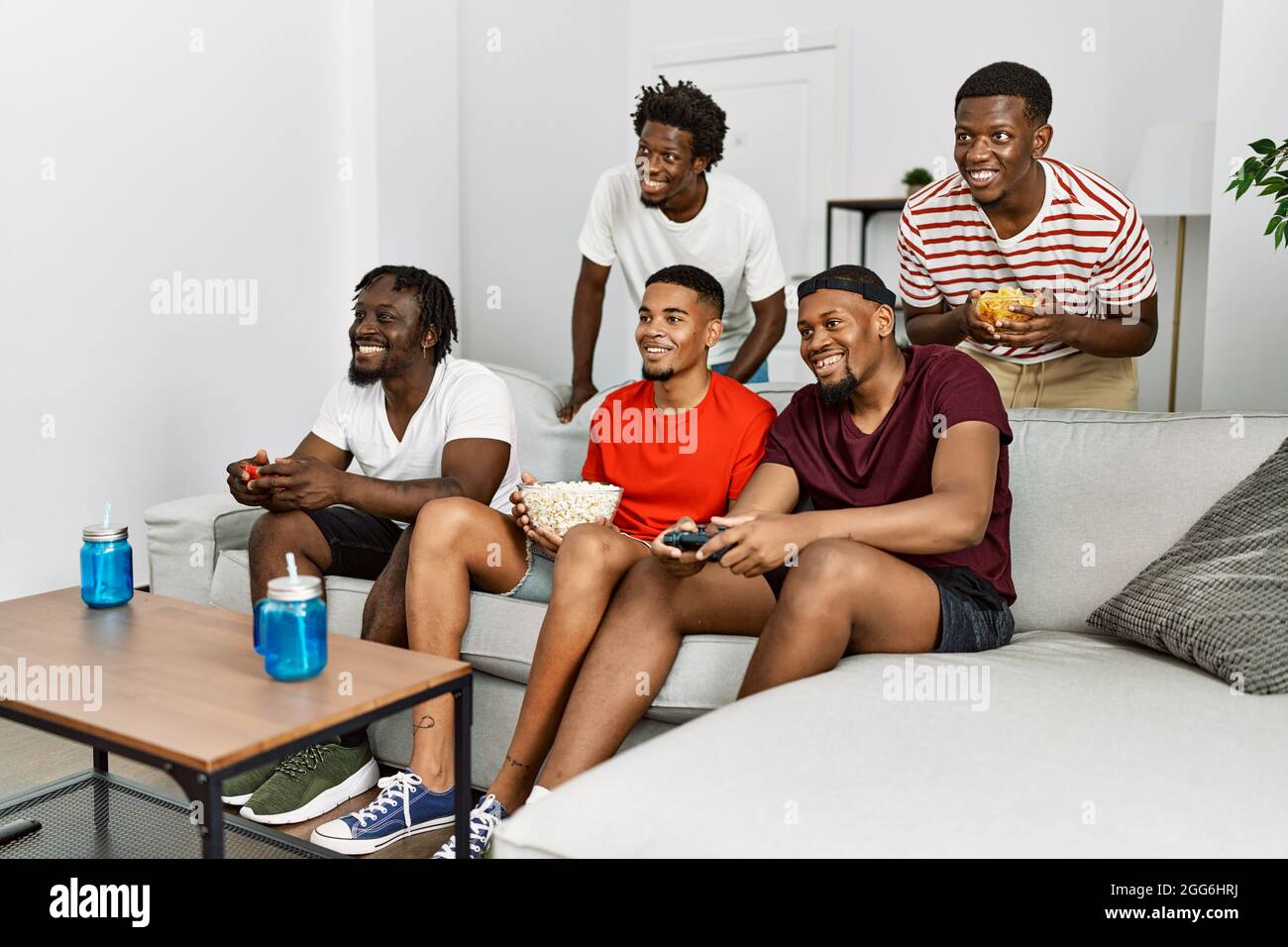 Young african group of friends sitting on the sofa at home playing video  games looking positive and happy standing and smiling with a confident  smile Stock Photo - Alamy