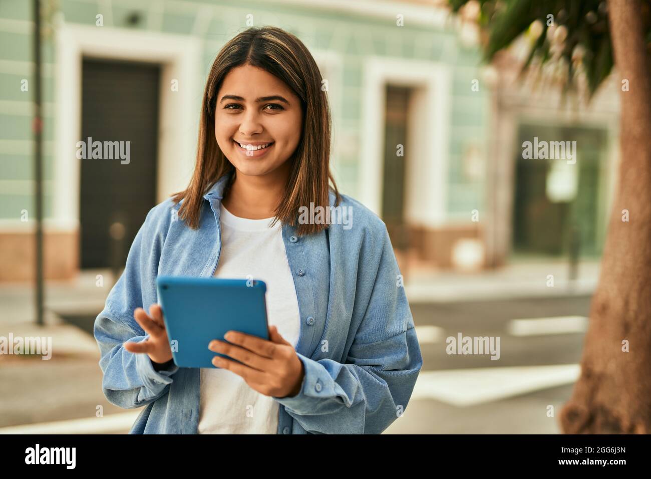 Young latin girl smiling happy using touchpad at the city Stock Photo ...
