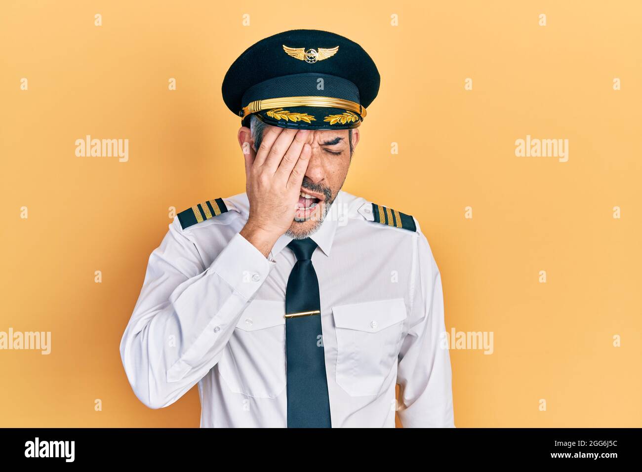 Handsome middle age man with grey hair wearing airplane pilot uniform  yawning tired covering half face, eye and mouth with hand. face hurts in  pain Stock Photo - Alamy