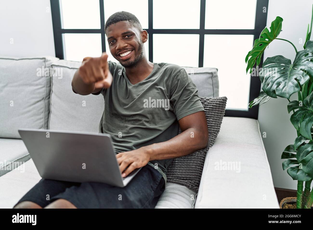 Young african american man using laptop at home sitting on the sofa ...