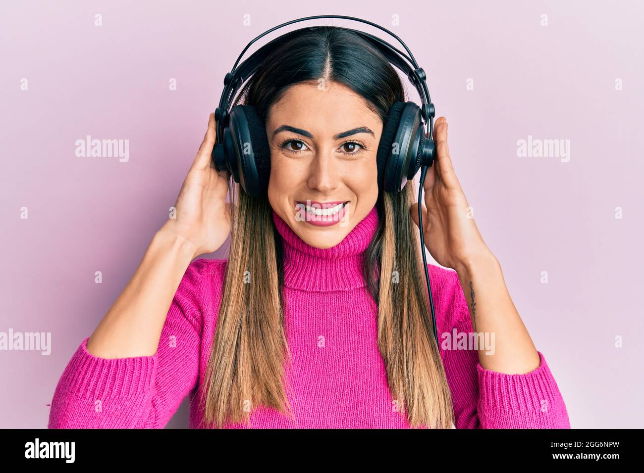 Young hispanic woman listening to music using headphones looking ...