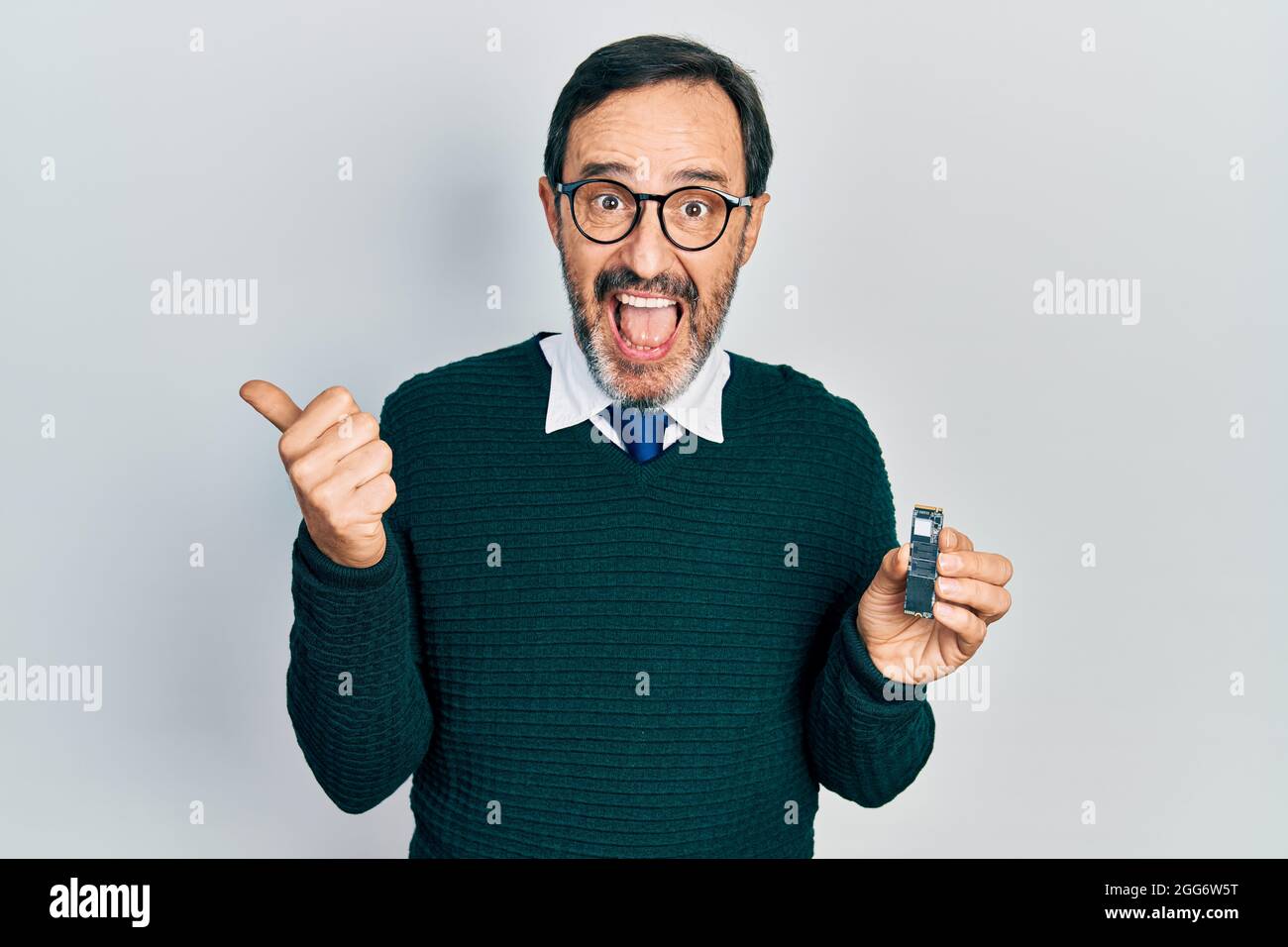 Middle age hispanic man holding ssd memory pointing thumb up to the ...
