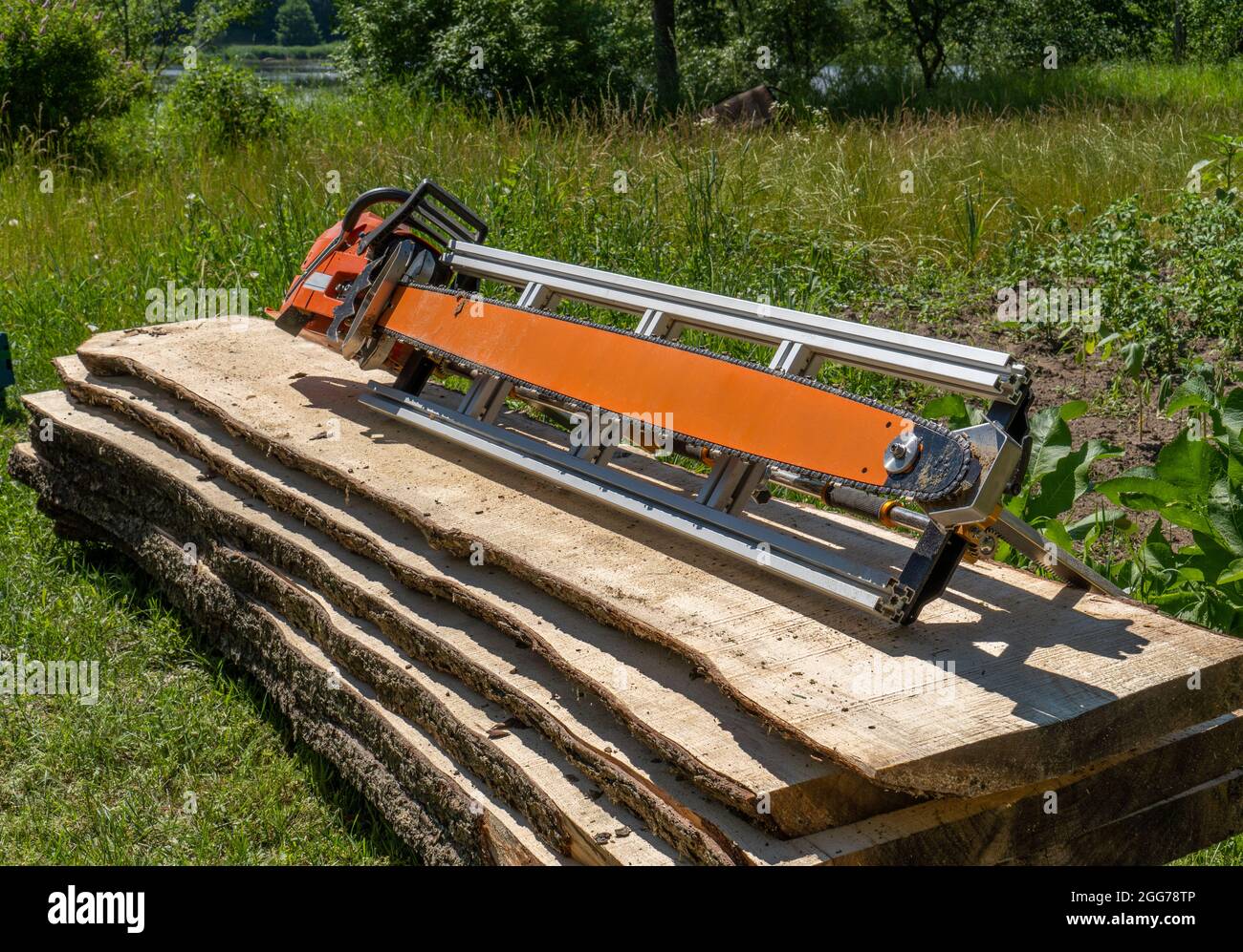 freshly cut spruce boards and chainsaws placed on a pile of boards  wooden boards cut and stacked on top of each other on top of which a chainsaw mill Stock Photo