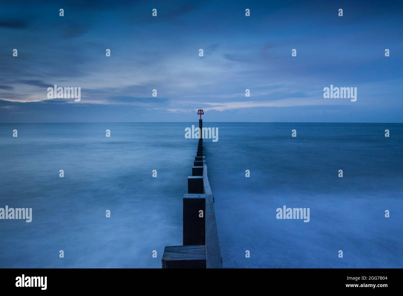 Smooth water effect around a wooden sea groyne at Southbourne beach, Bournemouth. Taken before sunrise, the scene takes on the colours of the Blue Hou. Stock Photo