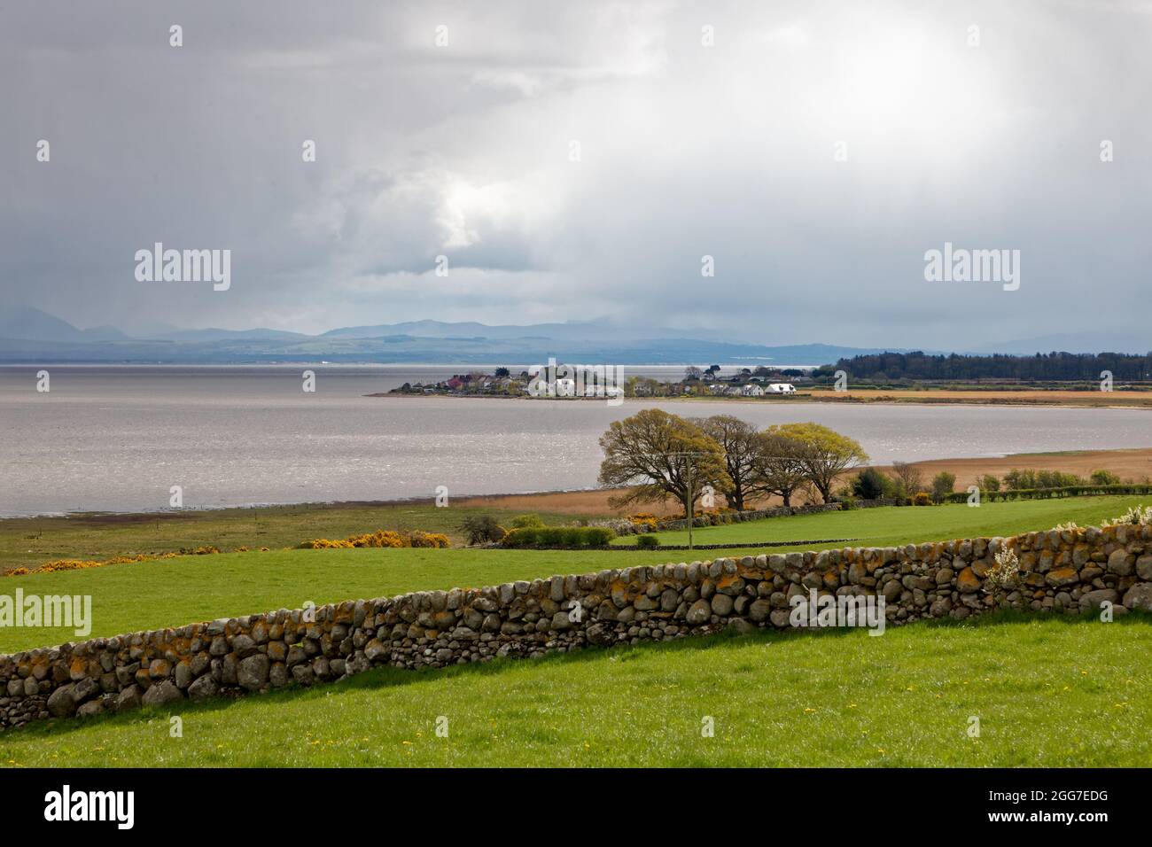 Carsethorn village and harbour and distant Lake District fells viewed from Drumburn Viewpoint near the mouth of the Nith Estuary Stock Photo