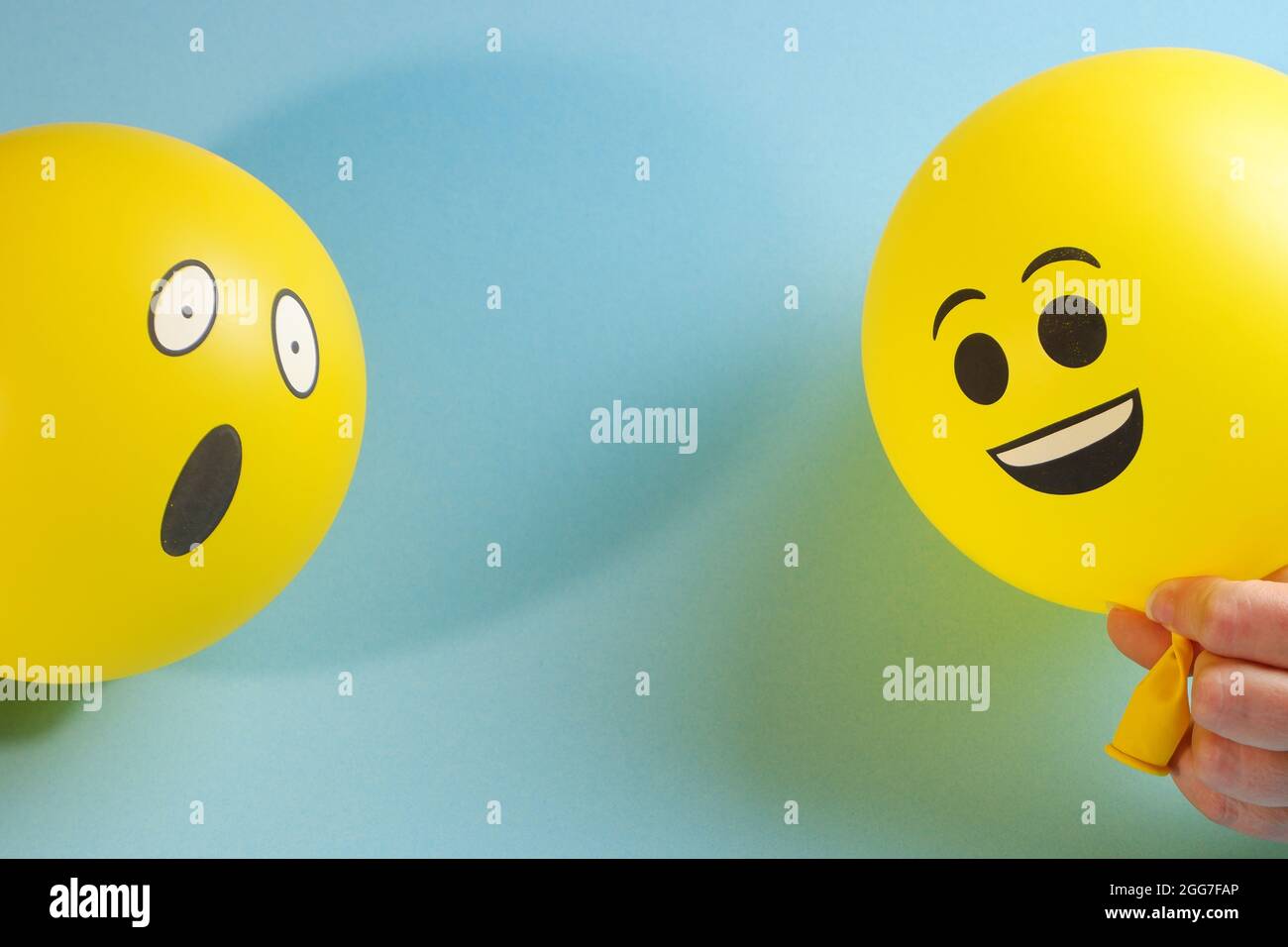 Yellow emoji balloons on a blue background. Stock Photo