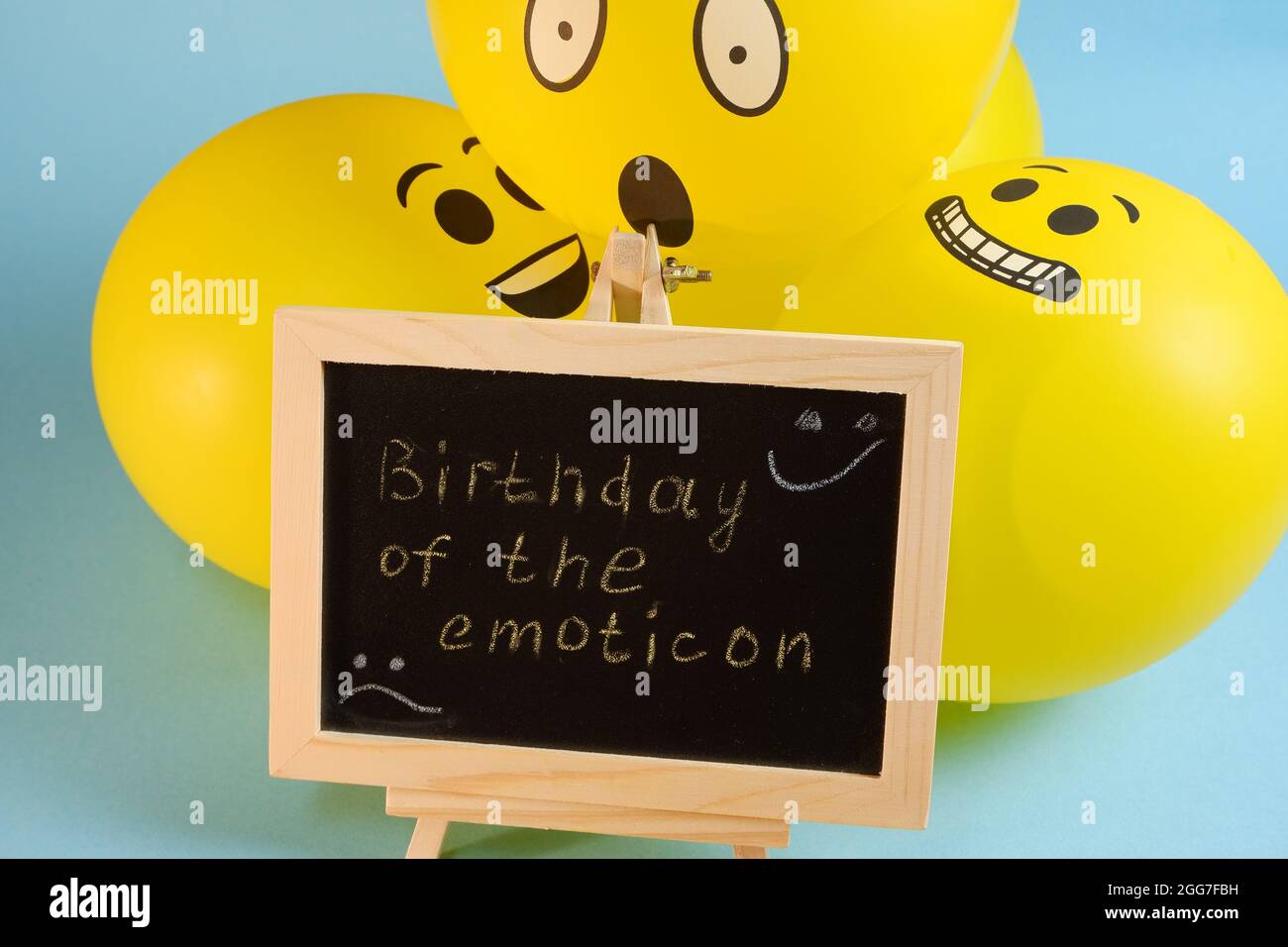 Yellow emoji balloons and a board with the inscription events on a blue background. Stock Photo