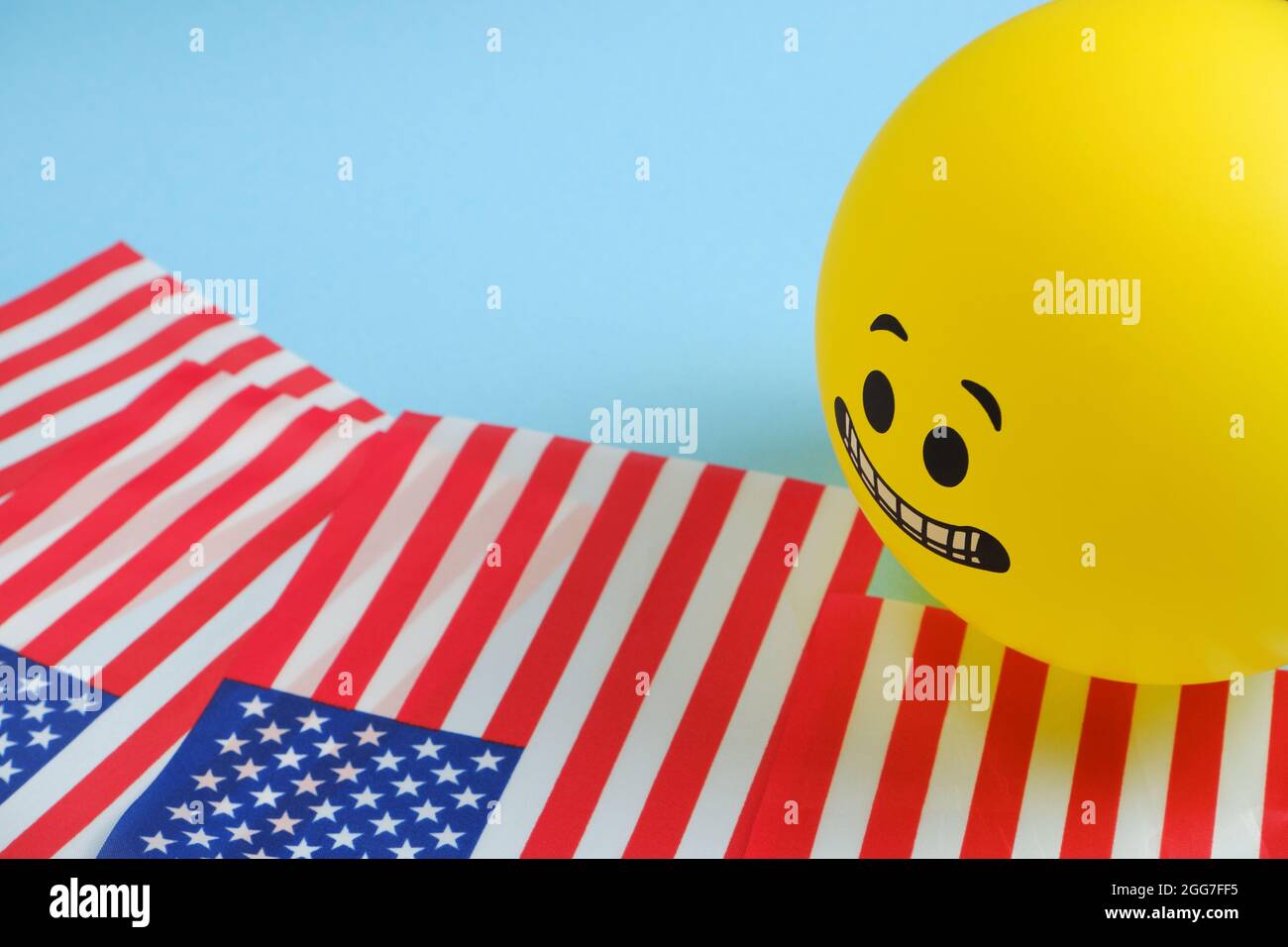 Yellow emoji balloons with American flags on a blue background. Stock Photo