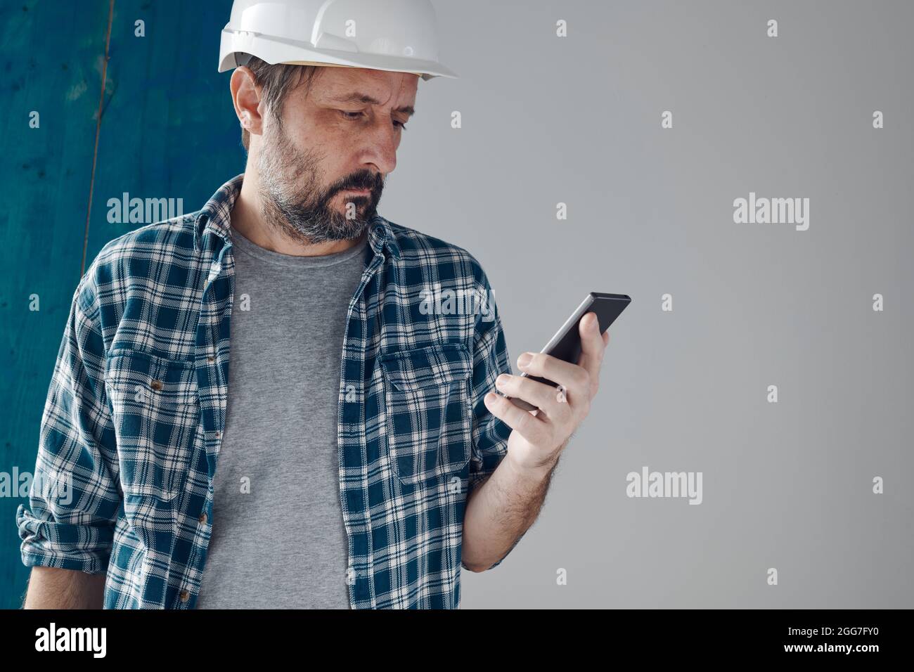 Construction engineer using smartphone on a morning break, relaxing and preparing for work Stock Photo