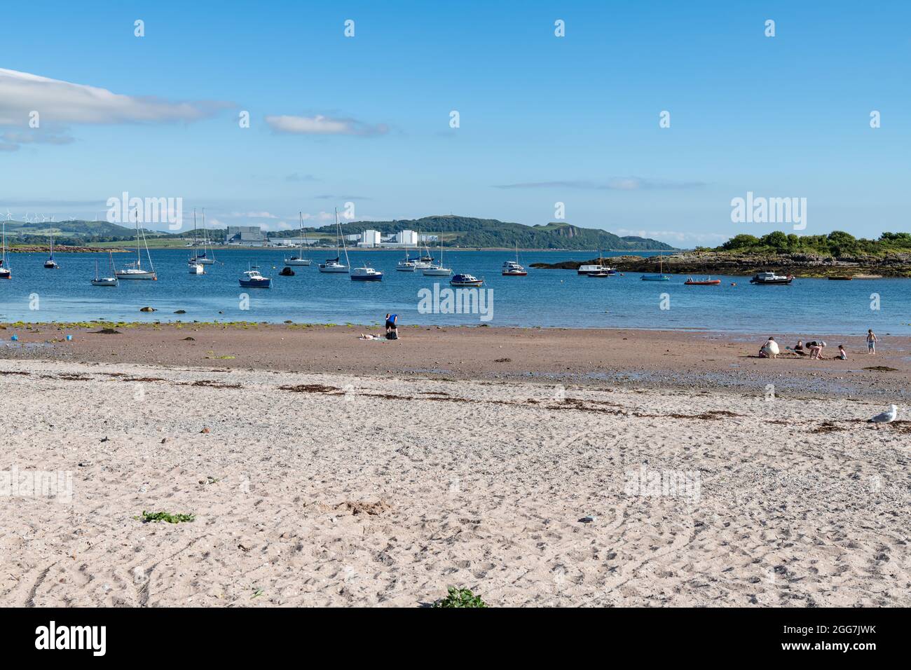 People on the beach in Millport with boats moored in Millport bay, Cumbrae, Scotland Stock Photo