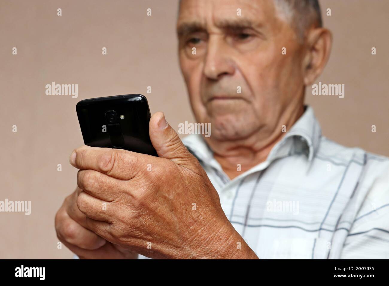 Elderly man using mobile phone, looking on smartphone screen. Concept of online communication in retirement, sms, reading news Stock Photo