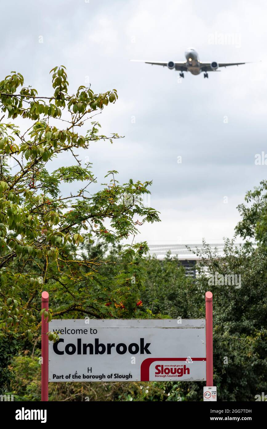 Airliner plane on approach to land at London Heathrow Airport, UK, over town sign for Colnbrook in the Borough of Slough. Flying over community Stock Photo