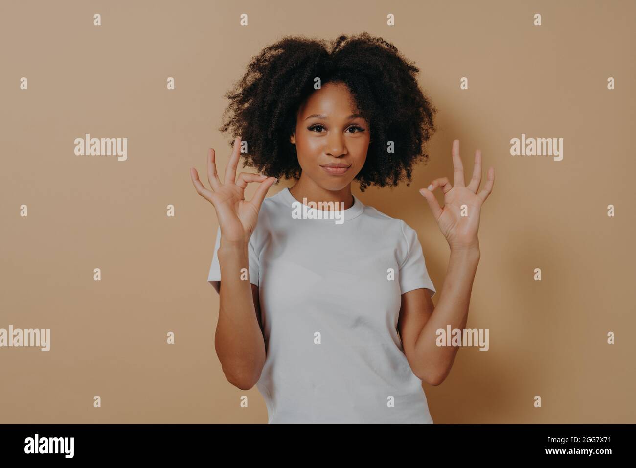 Young african american lady keeping both hands in okay gesture, isolated over brown background Stock Photo